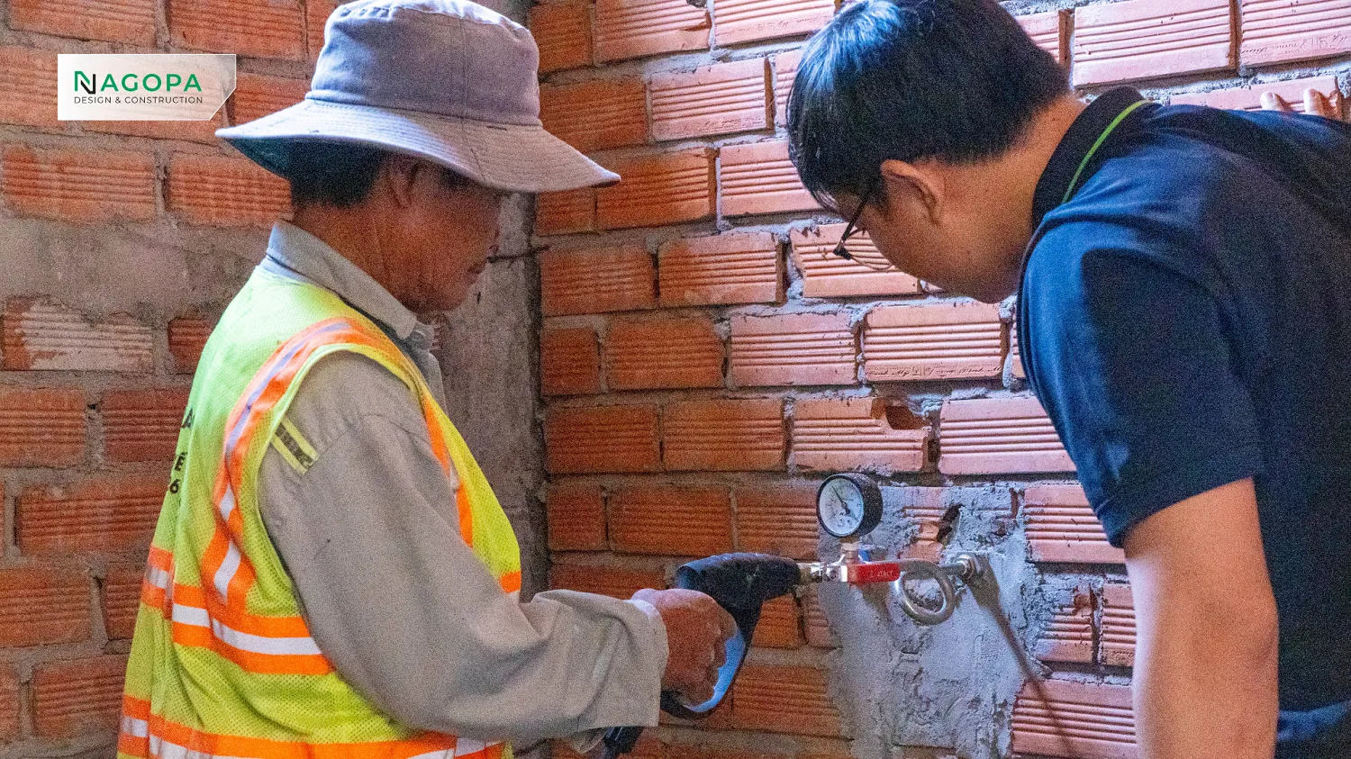 Kỹ sư xây dựng đang sử dụng bơm tay và đồng hồ để thử áp lực đường ống cấp nước, kiểm tra độ sụt áp.